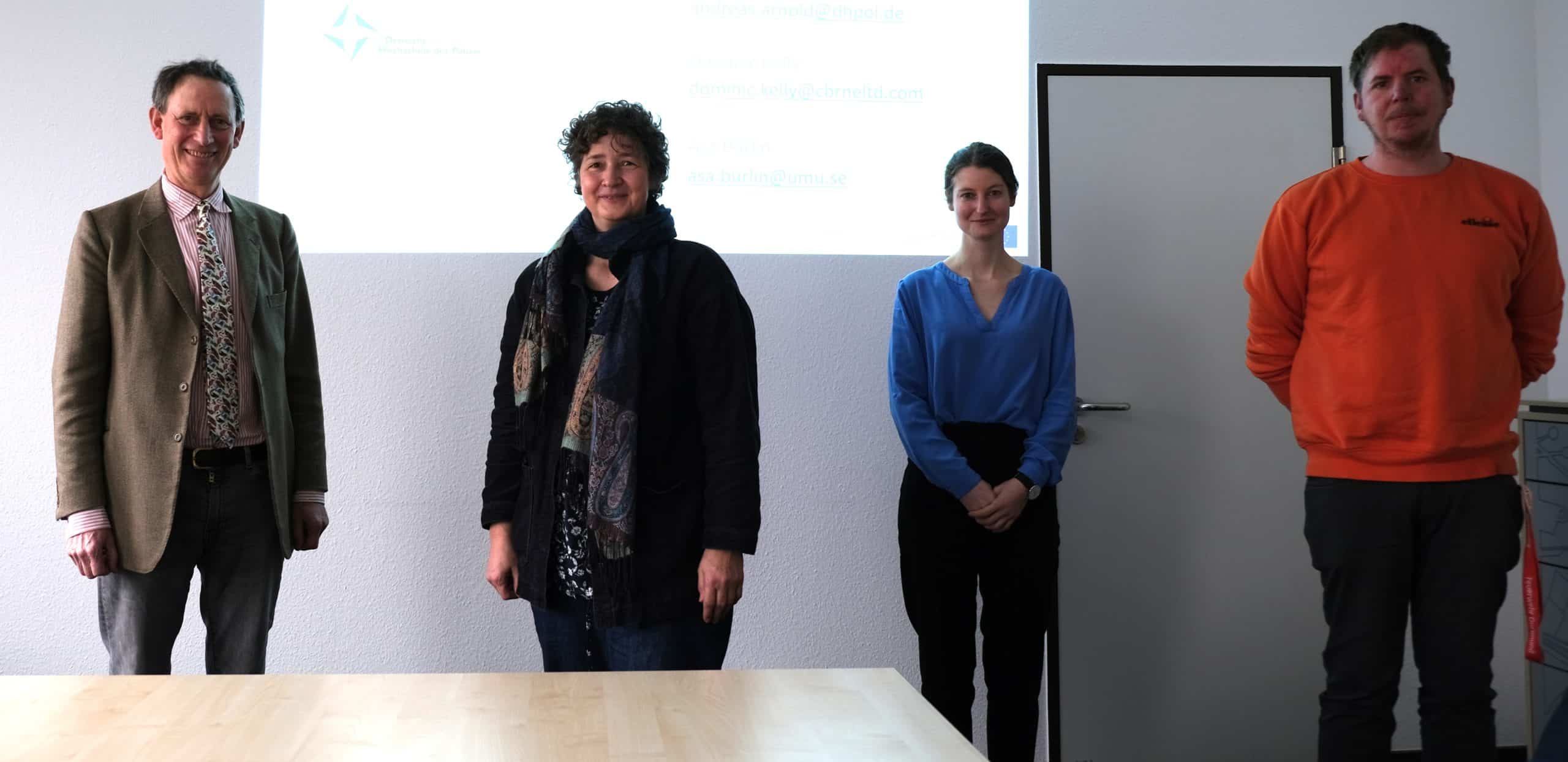 Four persons in a meeting room socially distanced with PROACTIVE logo projected in background