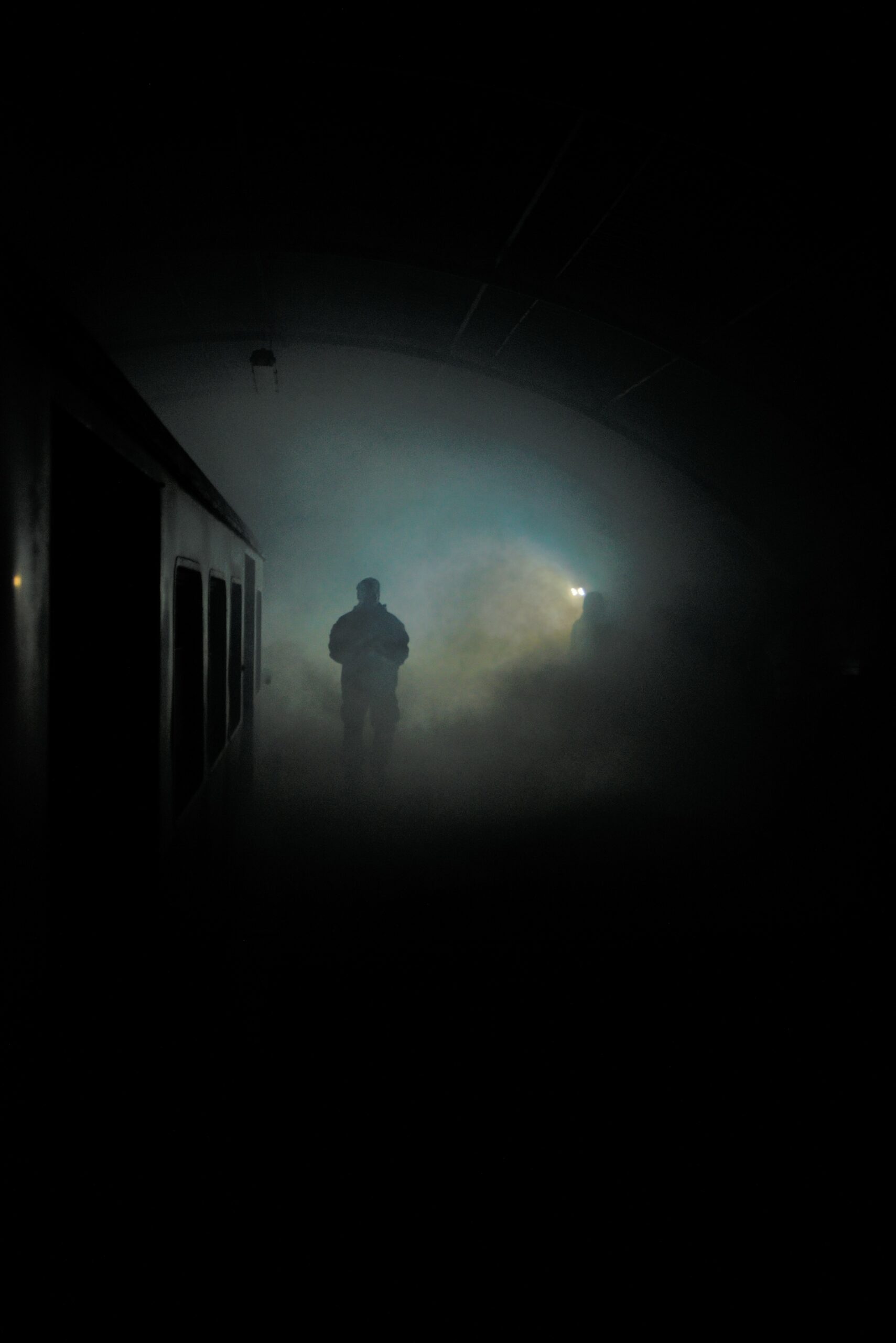A man in the dark can be seen through the fog appearing near to the train platform. The train wagon is also slightly visible.